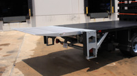 A galvanized Tuckunder liftgate in the up position on a flatbed truck