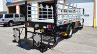 A Tommy Gate High-Cycle Gas Bottle Rack Railgate on a stake body work truck