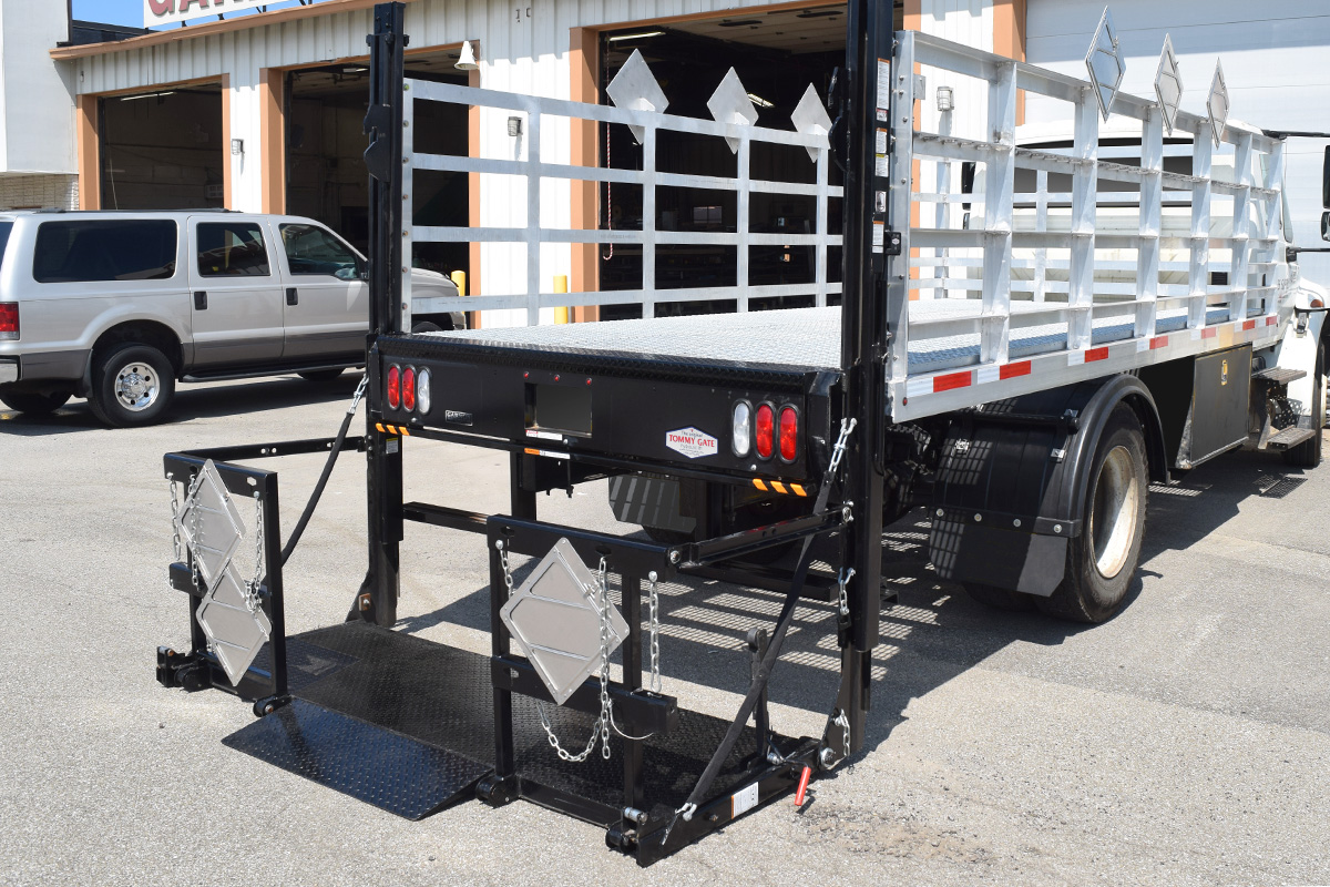 A Tommy Gate High-Cycle Gas Bottle Railgate on a Stake Truck